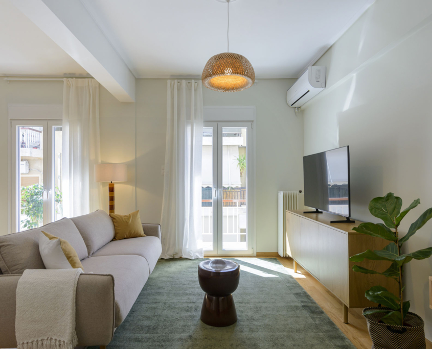 Bright living room with smart TV, air conditioning and balcony access in furnished long stay apartment in Ano Petralona, Athens