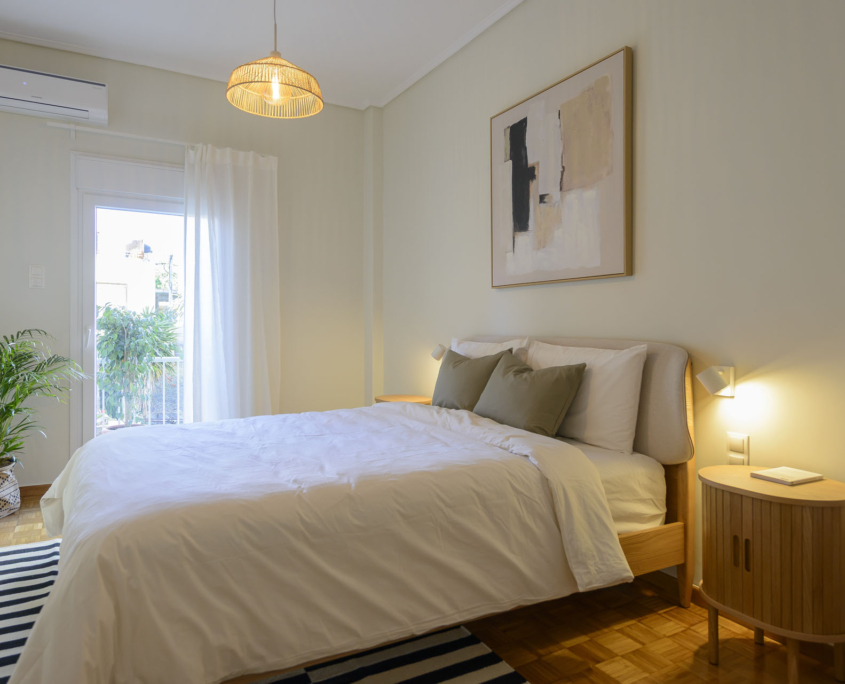 Bright bedroom with double bed, air conditioning and balcony access in furnished long stay apartment in Ano Petralona, Athens