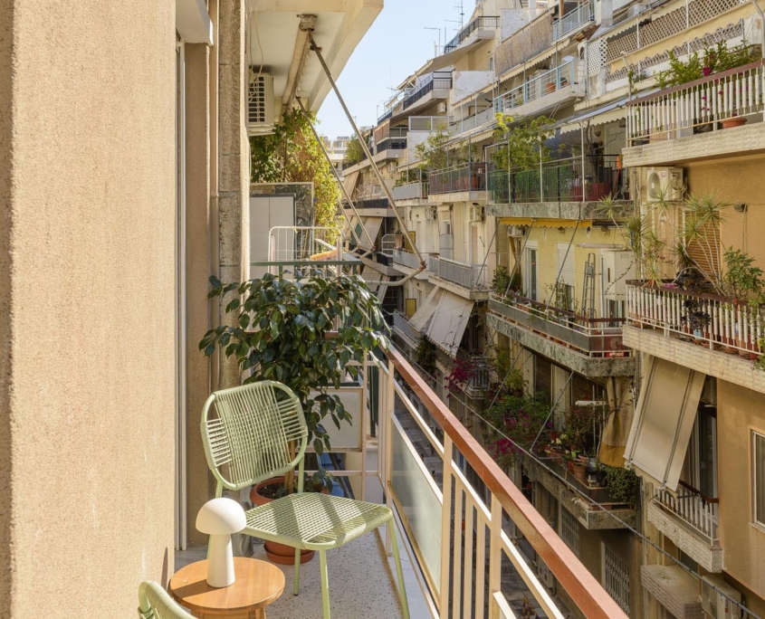 Sunny balcony with outdoor seating and neighborhood view in furnished long stay apartment in Ano Petralona, Athens