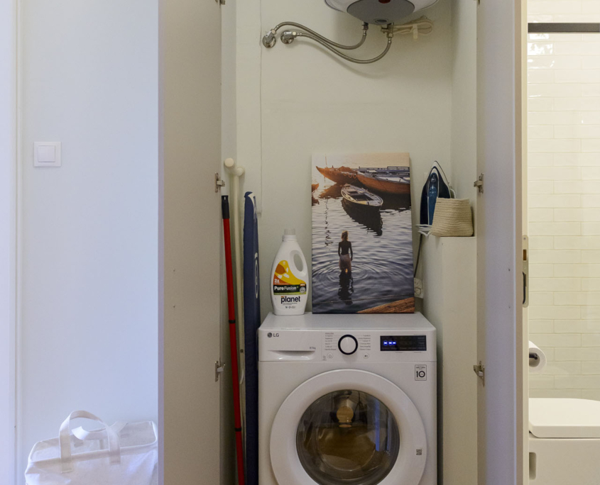 Built-in laundry area with new washer dryer, ironing board and hot water boiler in furnished long stay apartment in Ano Petralona, Athens