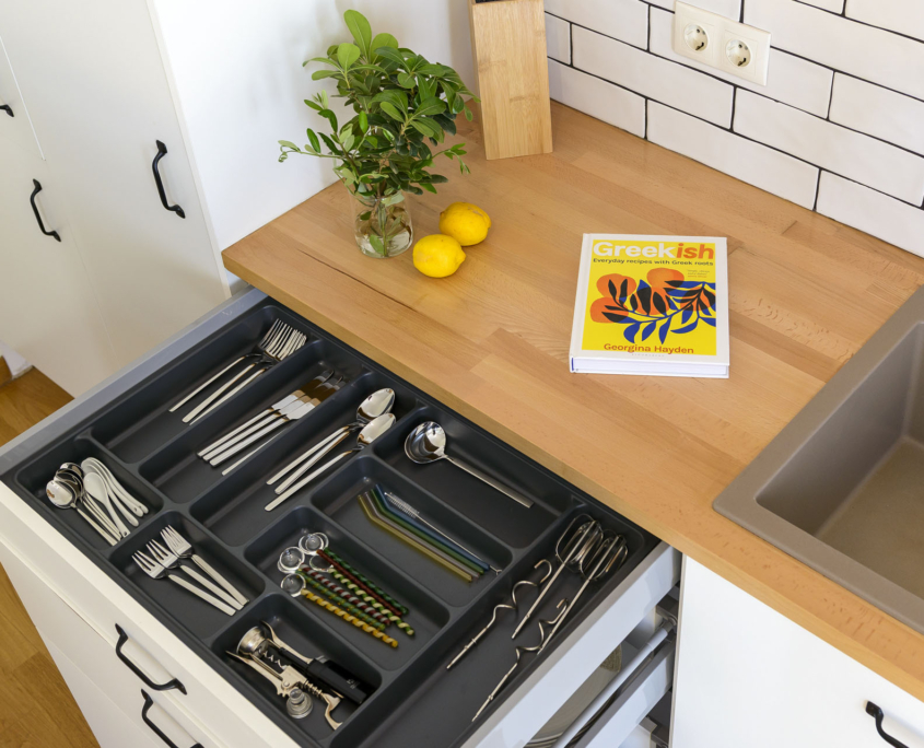 Fully equipped kitchen with organized cutlery drawer and wooden countertop in furnished long stay apartment in Ano Petralona, Athens